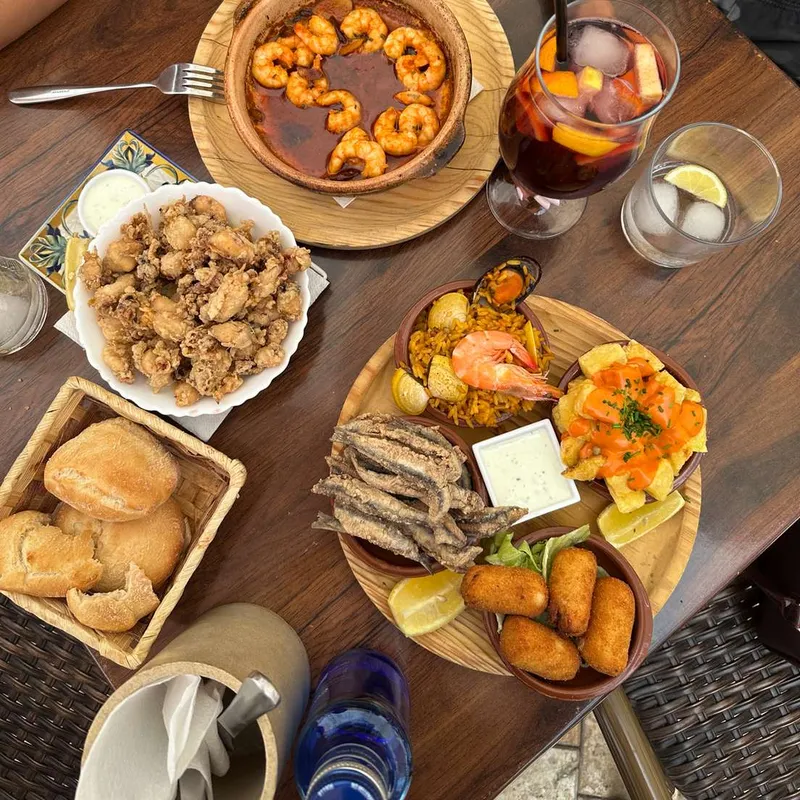 Prawns in garlic oil, fried baby squid, fried anchovies and croquettes on a wooden table