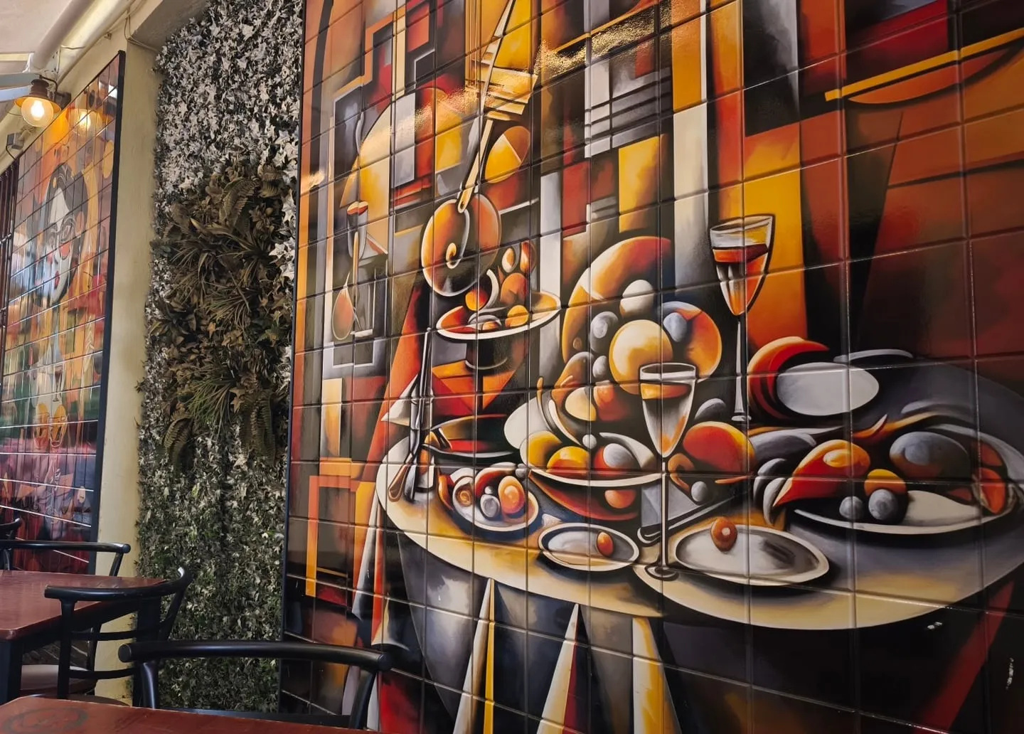 Tables in Pasaje Campos in front of a large tile mural of a cubist banquet