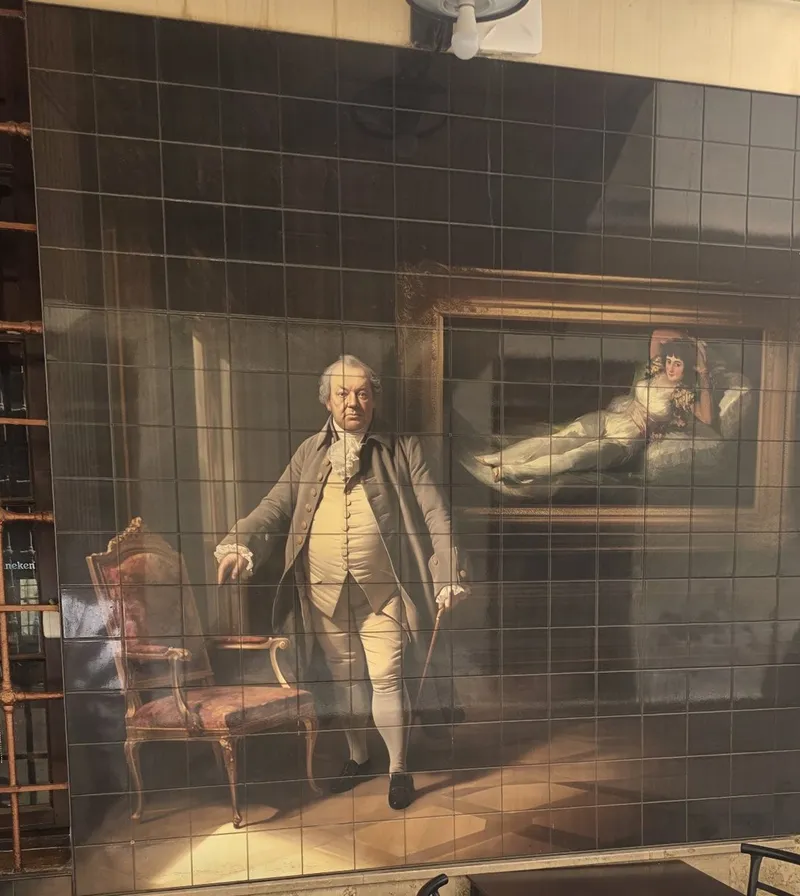 Tile mural in the passage: an eighteenth-century gentleman with a cane in a salon, with a large framed painting behind him